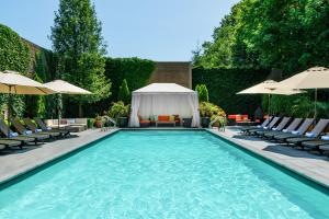 a swimming pool with lounge chairs and umbrellas at The J House Greenwich Hotel in Greenwich
