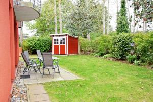 un patio trasero con una mesa y sillas y un cobertizo rojo en Ferienwohnung Moewennest mit Terra, en Middelhagen