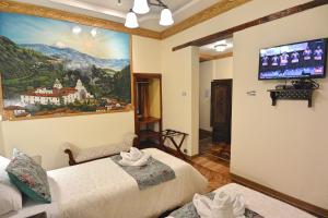 a room with two beds and a tv on the wall at Hotel La Basílica Quito in Quito