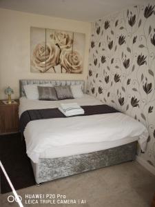 1 dormitorio con 1 cama con flores en la pared en RICHFLO Holiday Rentals en Mánchester