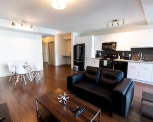 sala de estar con sofá de cuero negro y mesa en Mayfair by Corporate Stays en Edmonton