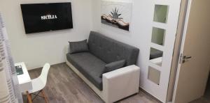 uma sala de estar com um sofá e uma televisão na parede em The Ladybug Holiday House - Locazione Turistica em Siracusa
