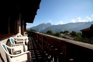 una fila di sedie bianche sedute su un balcone con vista sulle montagne di Nonostantetutto B&B a Pieve di Cadore