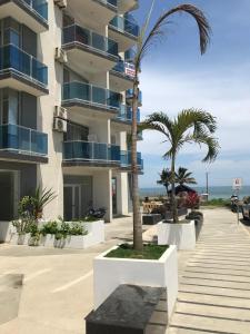a building with palm trees next to the beach at Espectacular, frente al mar in Tonsupa