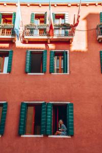 a woman looking out the window of a red building at Palazzo San Luca in Venice