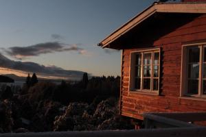 une cabane en rondins avec un coucher de soleil en arrière-plan dans l'établissement Pajaro Azul, à San Carlos de Bariloche