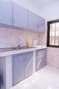 a kitchen with white cabinets and a sink at Appartement F4 Climatisé RDC à Totsi près de la maison ADEBAYOR in Lomé