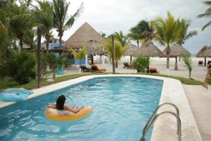 斯島的住宿－Hotel Puerto Holbox Beach Front，度假胜地游泳池里木筏上的女人