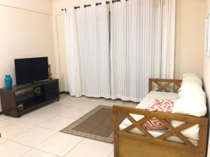 uma sala de estar com uma televisão e um sofá em Apartamento na Praia da Prainha - Arraial do Cabo. em Arraial do Cabo