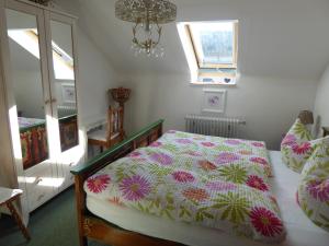 a bedroom with a bed with a floral comforter and two windows at Schwarzwald-Ferienwohnungen Begert in Baiersbronn