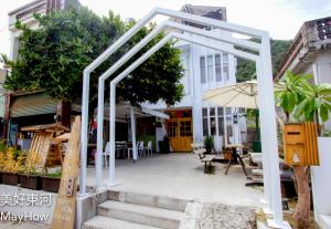 a white pergola in front of a white house at Mayhow Donghe in Donghe