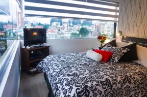 1 dormitorio con 1 cama, TV y ventana en Executive Suite, en Quito