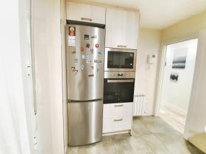 a stainless steel refrigerator in a kitchen with white cabinets at Apartamento céntrico in Zaragoza