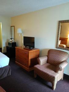 サンアントニオにあるKnights Inn San Antonio near Frost Bank Centerのベッド、椅子、テレビが備わるホテルルームです。