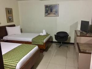 una habitación de hotel con 2 camas y una silla en Hotel Ambassador, en San José