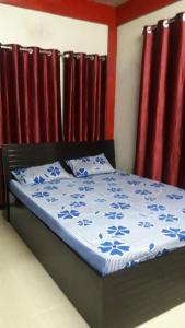 a bed with a blue comforter and red curtains at Rani Homestay in Cherrapunji