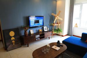 sala de estar con TV y pared azul en Sea View Apartment Qingdao North Railway Station Branch en Xiazangtuan