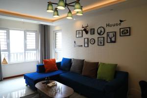 a living room with a blue couch with colorful pillows at Sea View Apartment Qingdao North Railway Station Branch in Xiazangtuan