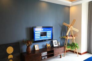 ein Wohnzimmer mit einem TV an einer blauen Wand in der Unterkunft Sea View Apartment Qingdao North Railway Station Branch in Xiazangtuan