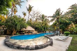 ein Swimmingpool in einem Resort mit Palmen in der Unterkunft Rumah Antony in Gili Trawangan