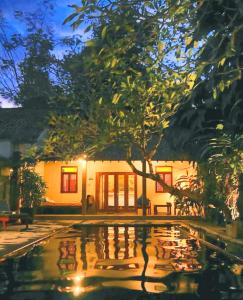a pool in front of a house at night at D'omah Yogya Hotel in Yogyakarta