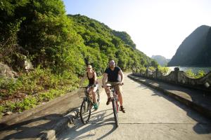 un hombre y una mujer montando bicicletas en un puente en Sunlight Cruise, en Ha Long