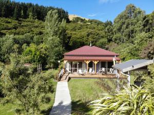 a house with a red roof and a walkway at Koromiko Cottage at Lochsloy Farmstay Little River in Little River