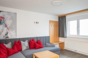 a living room with a couch with red pillows at Sunshine Appartements Schilchegger in Obertauern