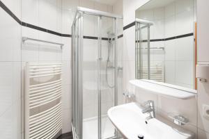 ein weißes Bad mit einer Dusche und einem Waschbecken in der Unterkunft Sunshine Appartements Schilchegger in Obertauern