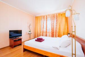 a bedroom with a white bed and a television at Centr Kvartir 25 in Minsk
