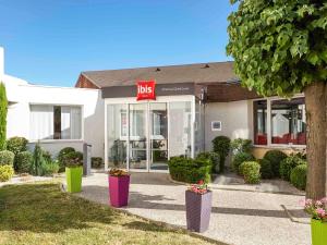 uma loja de bds com potes de flores em frente em ibis Chartres Ouest Luce em Chartres