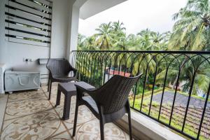 a balcony with chairs and a view of palm trees at Casa Legend Suites Candolim Goa in Candolim