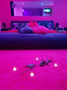 een slaapkamer met een bed met roze verlichting en kaarsen bij desirs-spa in Saint-Amarin