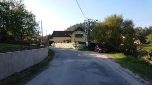 an empty road with a house and a red car on it at Apartmány Súľov 183 in Súľov