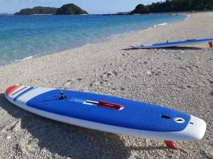 two surfboards sitting on a beach next to the water at Shima Stay holoholo in Zamami