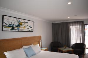 a hotel room with a bed and two chairs and a window at Best Western Quirindi RSL Motel in Quirindi