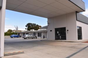 QuirindiBest Western Club Quirindi Motel的一座白色的大建筑,汽车停在停车场 更多20张照片