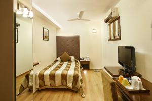 a bedroom with a bed and a flat screen tv at The Shalimar Hotel, Kemps Corner in Mumbai