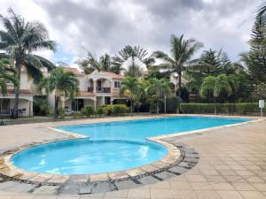 a swimming pool in front of a house with palm trees at Résidence Les Badamiers --- Exotica Villa in Centre de Flacq