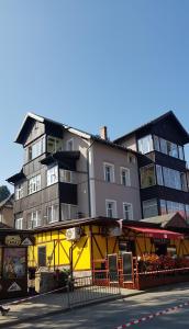 a tall building next to a yellow building at Apartament Różany in Karpacz