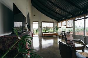 a room with a bed and chairs and windows at XOM Organic Farm Stay in Pleiku