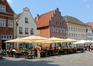 a group of people sitting at tables under umbrellas at Hotel Il Cavallino in Warendorf