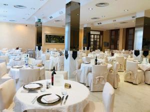 una sala da pranzo con tavoli bianchi e sedie bianche di Grand Hotel Ambasciatori Wellness & Spa a Chianciano Terme