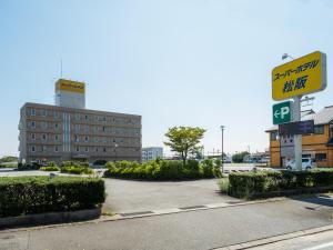 un parking en face d'un grand bâtiment dans l'établissement Super Hotel Matsusaka, à Matsuzaka