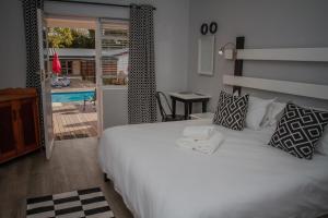 a bedroom with a white bed and a view of a pool at Aan de Eike Guest House in Swellendam
