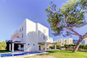 a white house with a tree in front of it at Beach Villa Pins by Sealand Villas in Cala de Sant Vicent