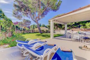 a patio with blue and white chairs and a grill at Beach Villa Pins by Sealand Villas in Cala de Sant Vicent