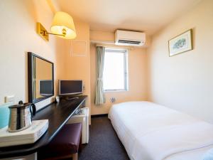 una camera d'albergo con letto e scrivania di Super Hotel Matsusaka a Matsuzaka