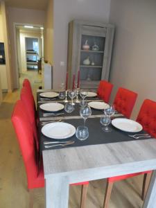 - une table à manger avec des chaises rouges, des assiettes et des verres à vin dans l'établissement Osea Oostende, à Ostende