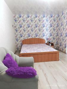 a bedroom with a bed and a couch with purple pillows at Apartment - Generala Petrova Street in Odesa